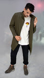 Homme portant un manteau Koto kaki croisé, non doublé, confectionné en tissu upcyclé, avec fermeture magnétique et coupe asymétrique, look urbain casual