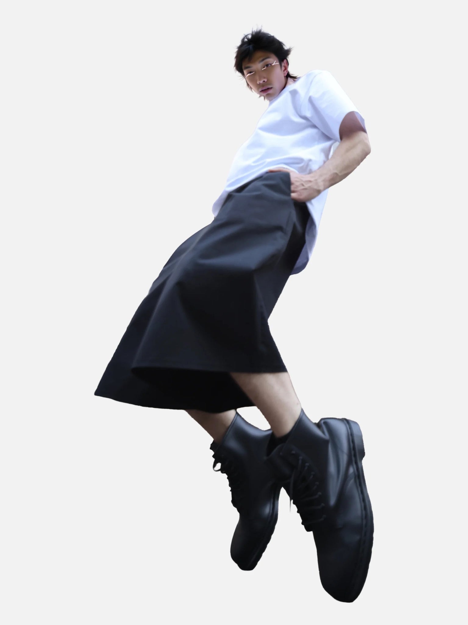 Homme en mouvement portant le bermuda Shaka noir, coupe ample inspirée du hakama japonais, associé à un t-shirt blanc et des boots noires