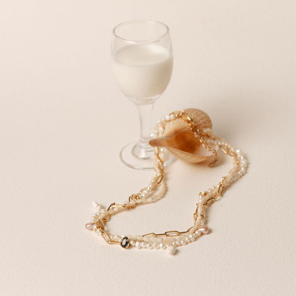 Collier multi-rangs en perles de culture blanches et rosées, orné de cristaux Swarovski et monté sur chaîne plaqué or.