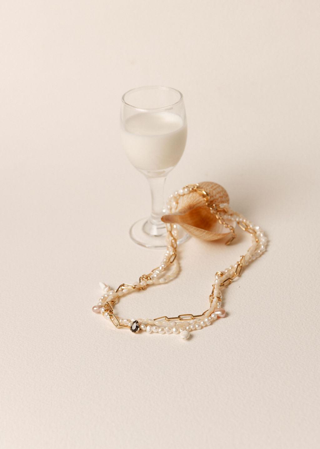 Collier multi-rangs en perles de culture blanches et rosées, orné de cristaux Swarovski et monté sur chaîne plaqué or.