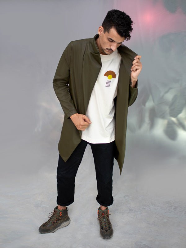 Homme portant un manteau Koto kaki croisé, non doublé, confectionné en tissu upcyclé, avec fermeture magnétique et coupe asymétrique, look urbain casual