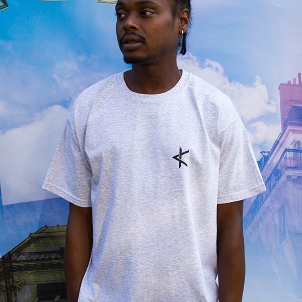 Homme portant un t-shirt gris clair à logo sérigraphié noir sur la poitrine, édition limitée fabriquée localement en coton écoresponsable
