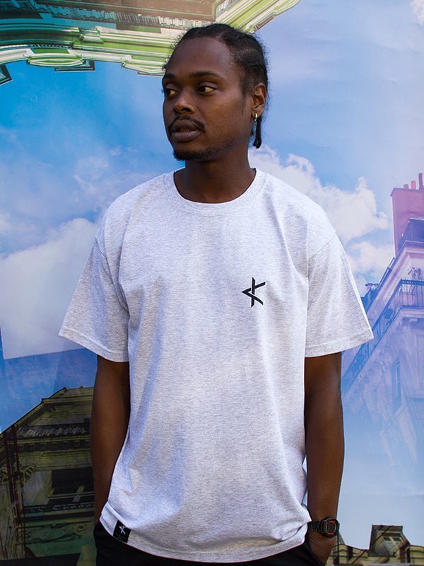 Homme portant un t-shirt gris clair à logo sérigraphié noir sur la poitrine, édition limitée fabriquée localement en coton écoresponsable