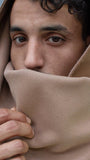 Portrait rapproché d’un homme portant une écharpe beige en polyester recyclé, portée en capuche et cache-cou, avec finition douce et fermeture invisible par aimants